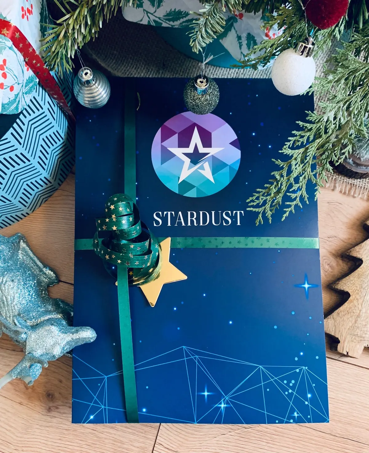 Stardust-Sternmappe mit grüner Schleife unter dem Weihnachtsbaum